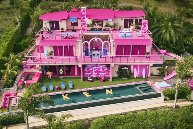 An image of Barbie's DreamHouse mansion, all pink with a pool at the front.