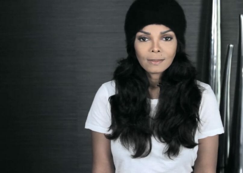 Janet Jackson sitting, looking at the camera.