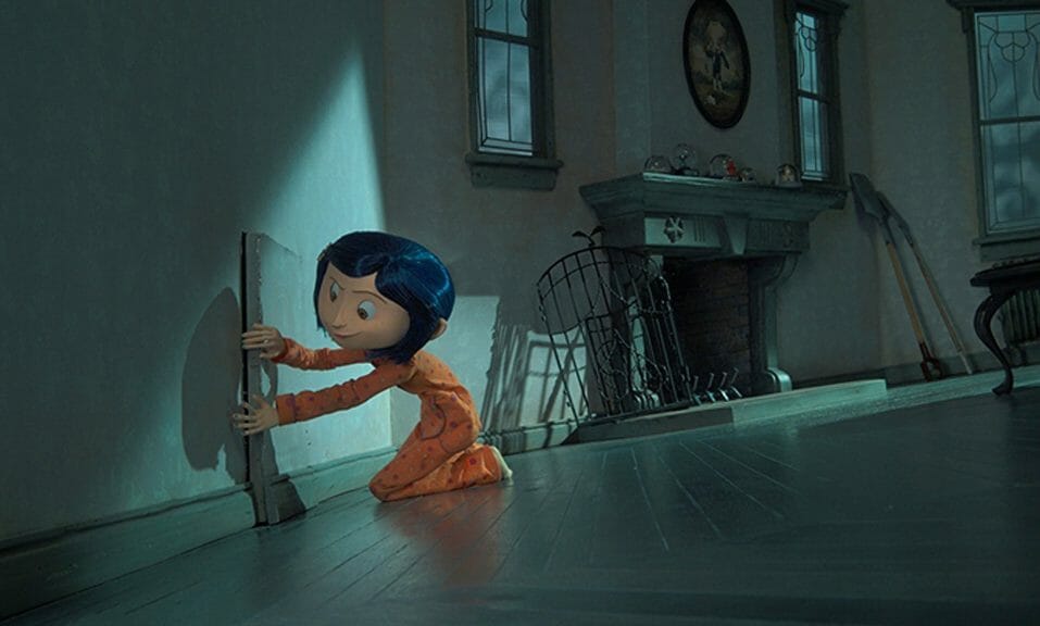 Coraline kneels down and tries to open a small, secret door in her family's new house. 