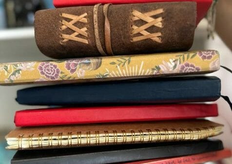 woman holding a stack of journals