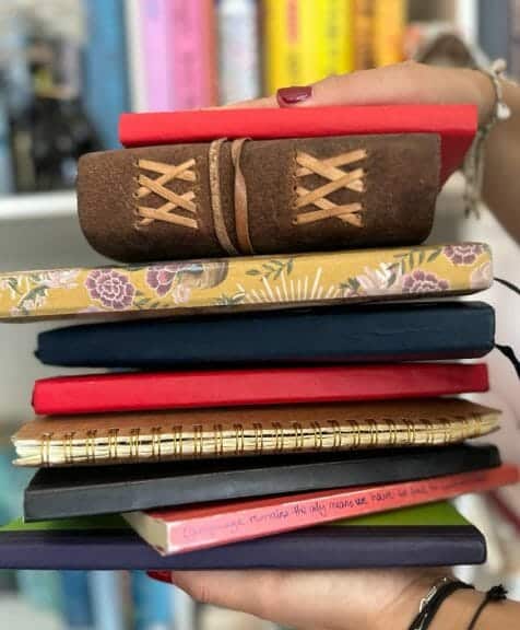 woman holding a stack of journals