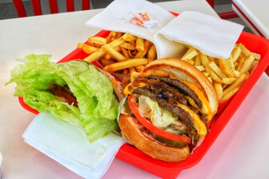 In-N-Out Double-Double cheeseburgers done protein style (left) and animal style (right), and two french fries in a tray