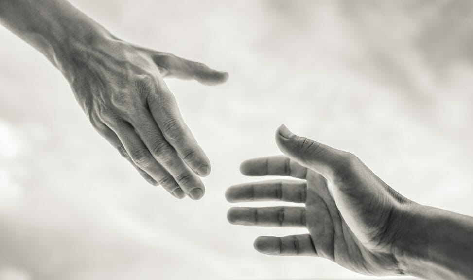 A black and white image of two hands trying to grab each other's from opposite ends.