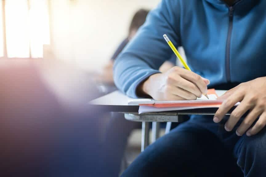 Student taking a test in class with paper and pencil.