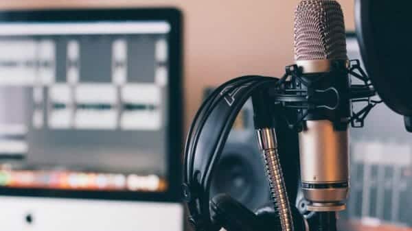 Photograph of a microphone and headphones with a computer in the background.