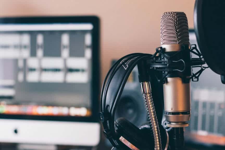 Photograph of a microphone and headphones with a computer in the background.