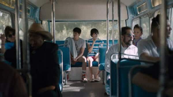 Aristotle and Dante observing people from the back of the bus. The camera frame centers the two to create focus.