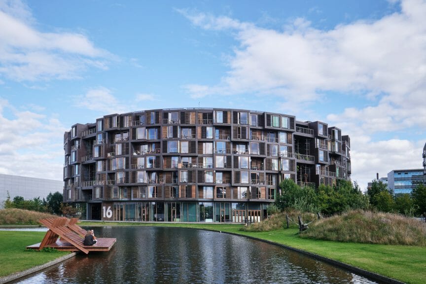 A circular-shaped apartment block behind a river.