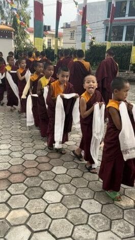 Buddhist child monks walk in a line as part of a religious ceremony.