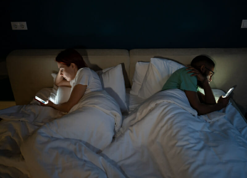 Couple in bed on their phones.
