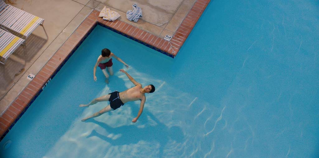 A view of Ari and Dante at the pool, with Ari floating and Dante instructing. They are the only two in the frame.