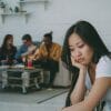 A woman looks isolated sitting separate from four other young adults.