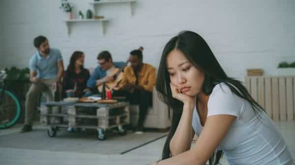 A woman looks isolated sitting separate from four other young adults.