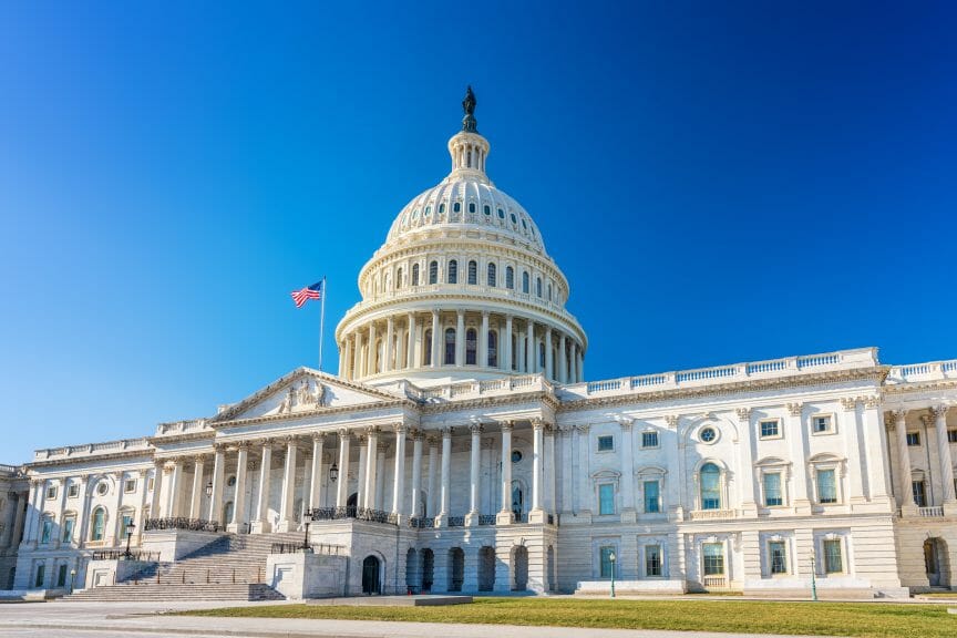 Capitol building, under blue sky with american flag in front. Iranians, Property Law, ban