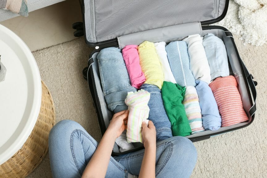 Woman packing up suitcase full of clothes