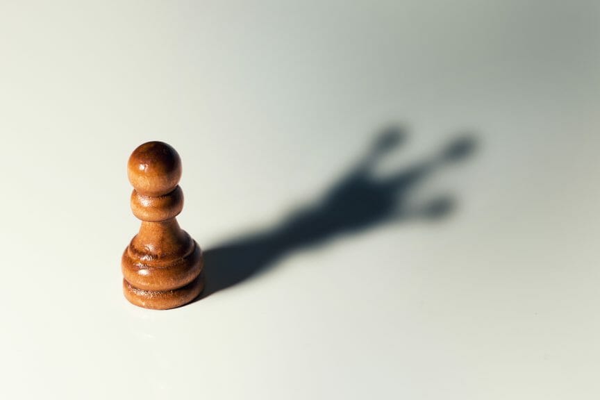 A pawn chess piece but its shadow is the queen. 