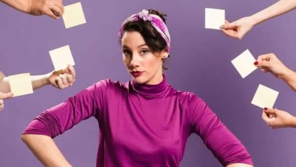 A woman facing the camera with hands surrounding her, holding post-it notes.