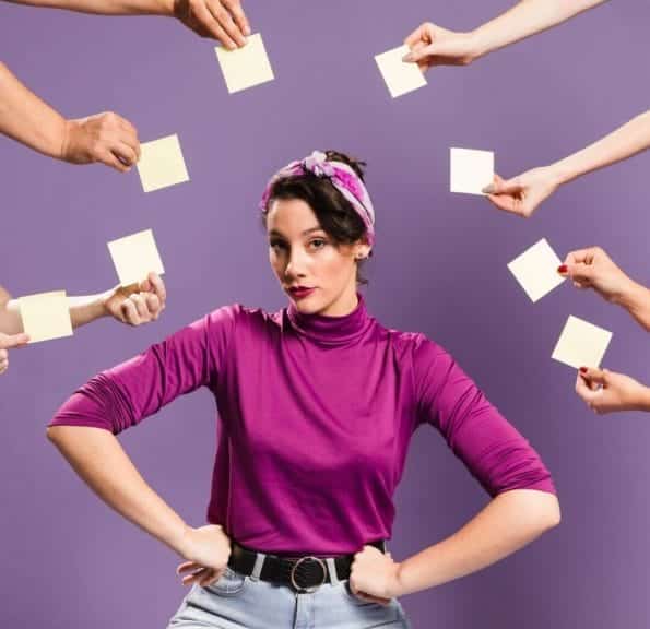 A woman facing the camera with hands surrounding her, holding post-it notes.