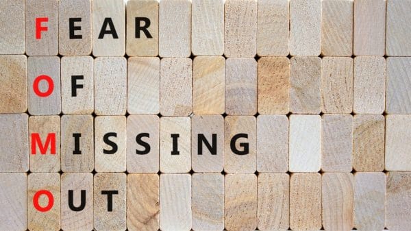 Wooden blocks spell our "fear of missing out," with the first letter of each word red.