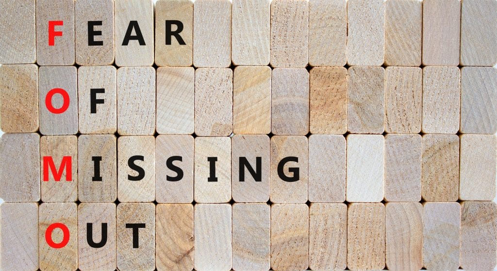 Wooden blocks spell our "fear of missing out," with the first letter of each word red.