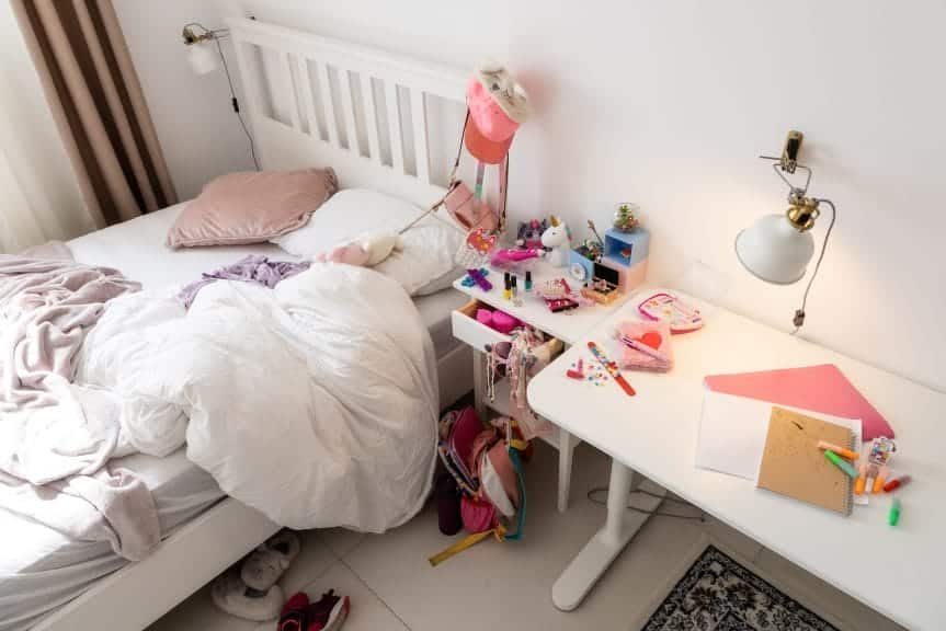 A picture of a messy room with an unmade bed.