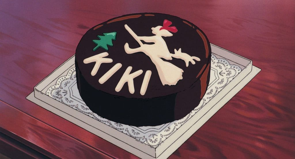 Image of a chocolate cake with a drawn girl, Kiki, on a boom. 