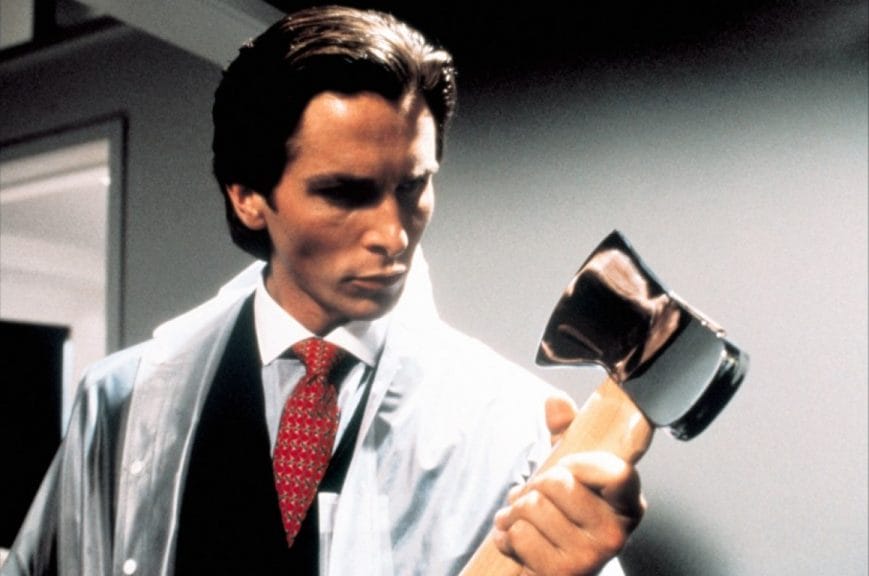 Christian Bale holding and staring at an axe in a scene from 'American Psycho.'