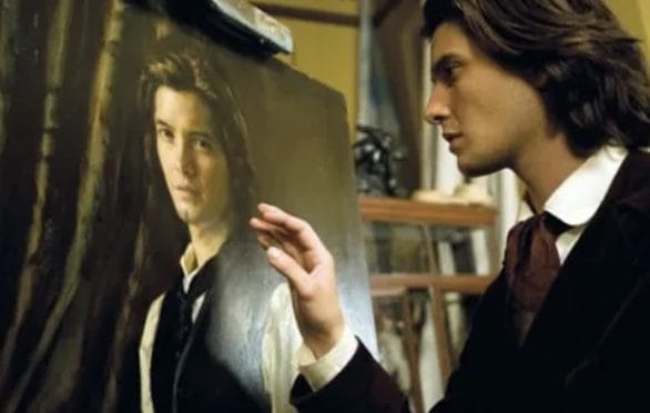 Ben Barnes as Dorian Gray, touching a portrait of himself.