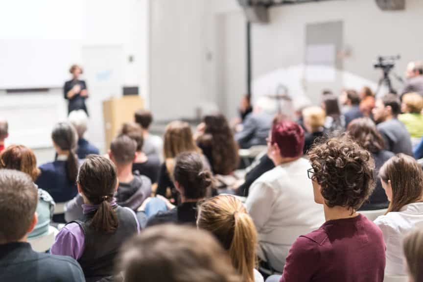 A typical college classroom filled with college students listening to the professor.