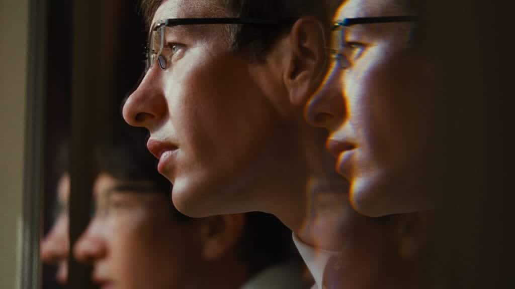 A refracted image of Barry Keoghan as Oliver Quick staring out of a window. 