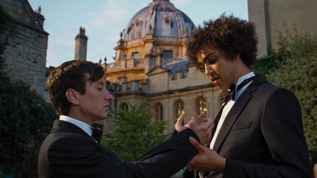 Still from 'Saltburn' of Archie Madekwe inspecting Barry Keoghan's cuff links. 