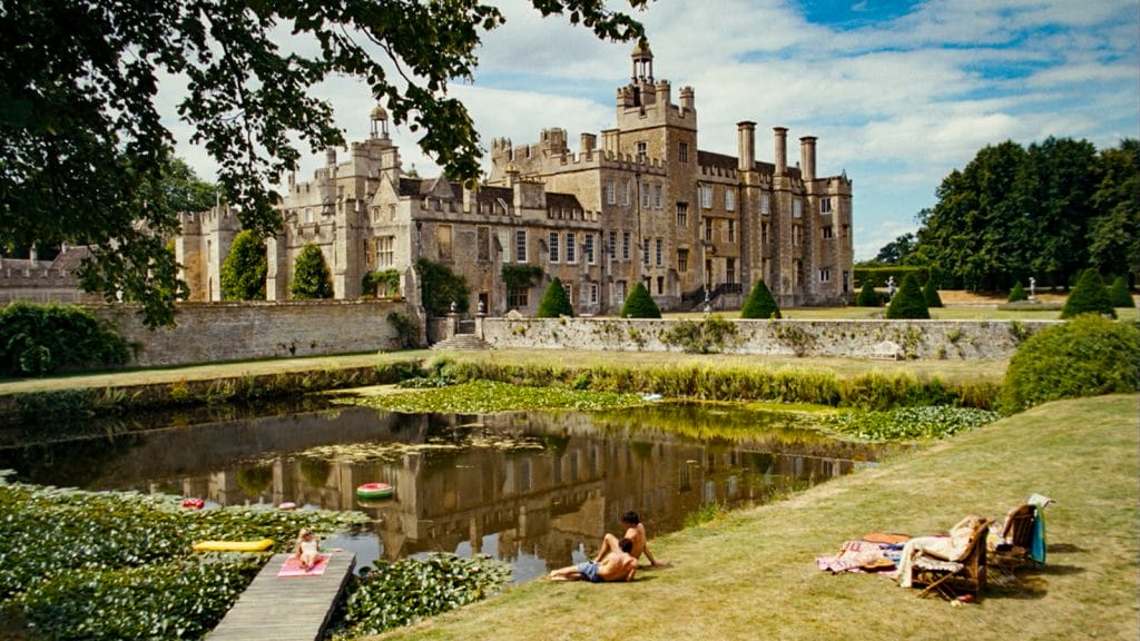 An old, castle-like house with a swimming pool in front. 