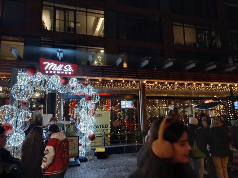 A building at night decorated with white and yellow lights and a sign that says "Mill St. Brewpub"