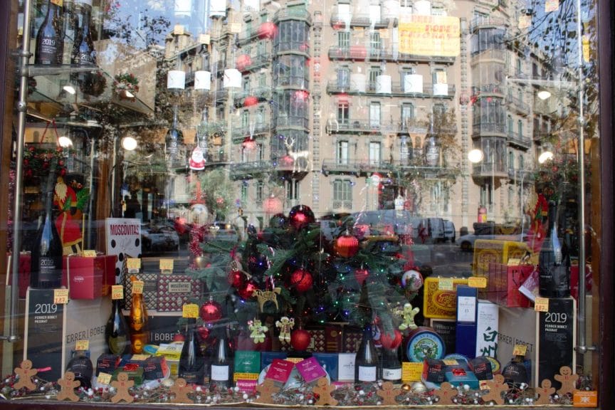 Barcelona's buildings reflected in the window of Queviures Múrria.