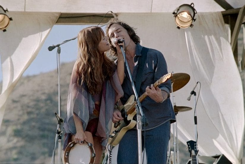 Daisy Jones and Billy Dunne perform a song together on stage at a music festival.