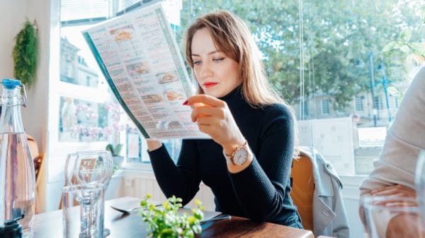 Gen Z woman looking at menu trying to decide on an order.