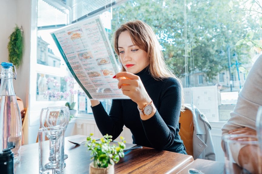 Gen Z woman looking at menu trying to decide on an order.