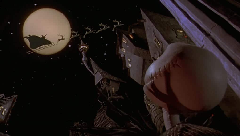 Jack Skellington looking up at Santa and the reindeer flying above. 