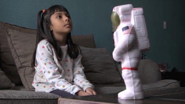 Adhara infront of a toy astronaut.