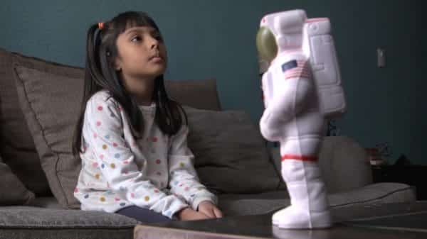 Adhara infront of a toy astronaut.