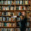 Blurry picture of a girl walking by a wall-length bookshelf, meant to represent the BookTok community.