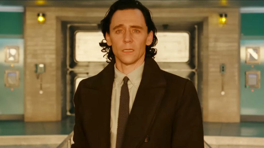 Loki in a suit and tie, looking toward the camera.