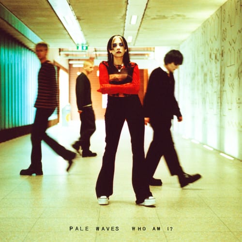 Cover art for Pale Wave's album 'Who am I?'. Heather Baron Gracie stands in the forefront of a corridor, with her bandmates mid-step behind her. 