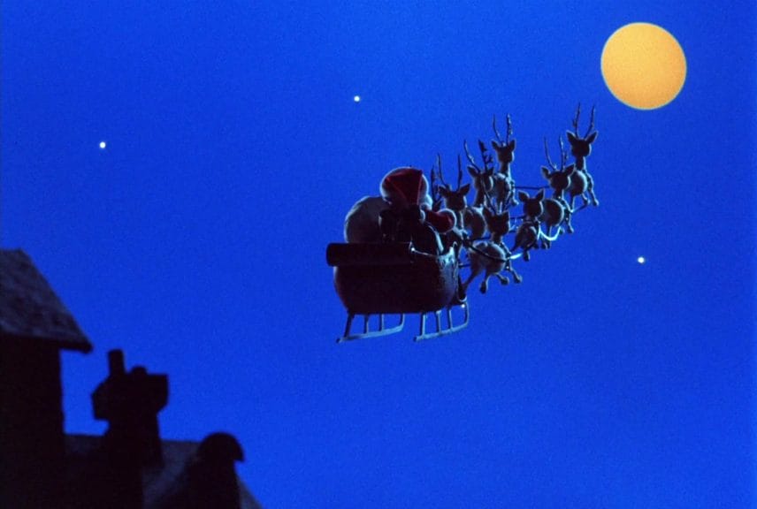 Santa and his reindeer fly off into the moonlit sky.