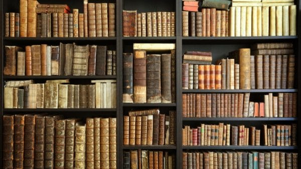 Dark bookshelf with old, bound books.