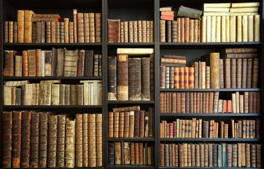 Dark bookshelf with old, bound books. Many Booktok creators pride themselves on their overflowing bookshelves.