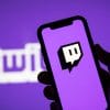 Twitch written in purple and white words with a phone held up showing the Twitch app logo.