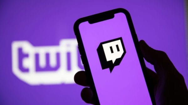 Twitch written in purple and white words with a phone held up showing the Twitch app logo.
