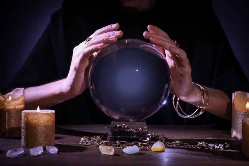 Soothsayer using crystal ball to predict future at table in darkness, closeup. 