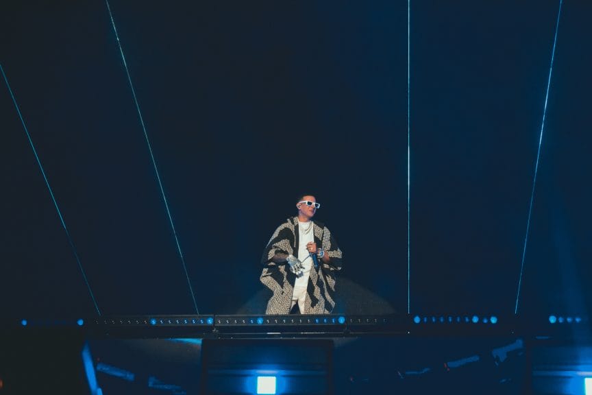 A man stood on stage with blue lasers pointing towards the sky